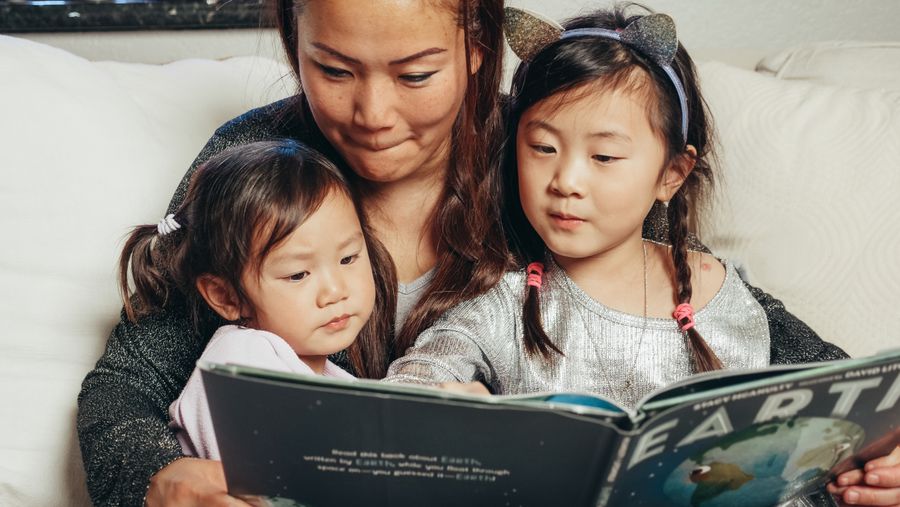 Anneleriyle birlikte kitap okuyan iki çocuk